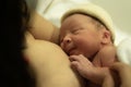 Lifestyle shot of woman holding adorable newborn baby girl skin on skin  immediately after birth laying happy on hospital bed in Royalty Free Stock Photo