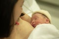 Lifestyle shot of woman holding adorable newborn baby girl skin on skin  immediately after birth laying happy on hospital bed in Royalty Free Stock Photo