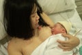 Lifestyle shot of woman holding adorable newborn baby girl skin on skin  immediately after birth laying happy on hospital bed in Royalty Free Stock Photo