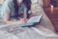 lifestyle soft image of pretty young woman sitting on her cozy bed and making notes to her diary. Fall season mood. Royalty Free Stock Photo