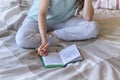 lifestyle soft image of pretty young woman sitting on her cozy bed and making notes to her diary. Fall season mood. Royalty Free Stock Photo