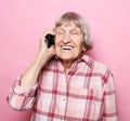 Old woman wearing casual talking on cell phone over pink background Royalty Free Stock Photo