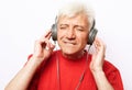 Lifestyle, tehnology and old people concept: Handsome old man in casual wear and headphones is listening to music Royalty Free Stock Photo