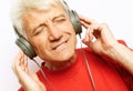 Lifestyle, tehnology and old people concept: Handsome old man in casual wear and headphones is listening to music Royalty Free Stock Photo