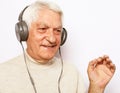 Lifestyle, tehnology and old people concept: image of an elderly gray-haired man listening to music with headphones Royalty Free Stock Photo