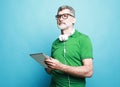 Happy senior bearded man wearing eyeglasses and headphones using digital tablet. Royalty Free Stock Photo