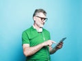 Happy senior bearded man wearing eyeglasses and headphones using digital tablet. Royalty Free Stock Photo