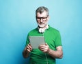 Happy senior bearded man wearing eyeglasses and headphones using digital tablet. Royalty Free Stock Photo