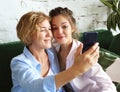 Lifestyle, tehnology and people concept: mature mother and her daughter making a selfie using smart phone