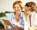 lifestyle, tehnology and people concept: mother and adult daughter using tablet computer at home