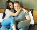 Lifestyle. tehnology and people concept: young couple with digital laptop resting on bed at home