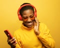 Young afro american female with dances in rhythm of melody over yellow background.