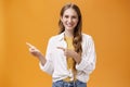 Waist-up shot of friendly pleasant and stylish young teenage female in blouse over t-shirt with cute wavy fair hair