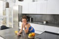 Lifestyle and workout. Young smiling woman in headphones, standing in kitchen with smartphone, drinking orange juice and Royalty Free Stock Photo