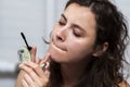 Lifestyle young woman doing makeup at home. The girl paints black mascara eyelashes. Royalty Free Stock Photo