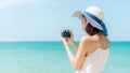 Lifestyle young woman relax on the summer beach.  Asia tourism people holding camera and take a photo Royalty Free Stock Photo