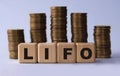 LIFO - acronym on wooden cubes on the background of stacks of coins