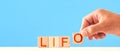 Lifo. man puts wooden cubes into the word lifo on a blue background. Last in first out concept.