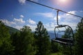 Lift on the background of mountains and green hills on sunny summer day. Empty bench of ski lift, tourism closed off quarantine. Royalty Free Stock Photo