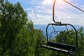 Lift on the background of mountains and green hills on sunny summer day. Empty bench of ski lift, tourism closed off quarantine. Royalty Free Stock Photo