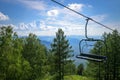 Lift on the background of mountains and green hills on sunny summer day. Empty bench of ski lift, tourism closed off quarantine. Royalty Free Stock Photo