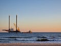 Lift boat and supply vessel setting up for an offshore wind farm at sunset in the USA.