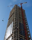 Lifting crane hoisting a weight at skyscraper cons