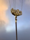 Lifting mechanism with a cargo hook of a tower crane  against the sunset sky. Close-up. The chains are hanging from the hook. Royalty Free Stock Photo