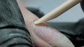 Lifting at the nail cuticle with a wooden orange stick. Hardware combined manicure. Manicure care procedure.