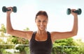 Lifting weights with a smile. Portrait of a sporty young woman working out with dumbbells. Royalty Free Stock Photo