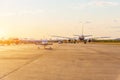 Light aircraft and a large wide-body jet in the distance are taxiing for takeoff, in the bright light of the setting sun Royalty Free Stock Photo