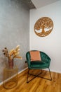 Light and airy interior living space with a green velvet armchair and a wooden tree ornament Royalty Free Stock Photo