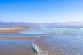 Light airy seascape. Wide sandy beach, sea waves, and cloudy sky