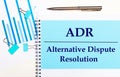 On a light background - light blue diagrams, paper clips and a sheet of paper with the text ADR Alternative Dispute Resolution.