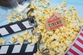 On a light background, a bucket with scattered popcorn, film, two movie tickets and a double for filming Royalty Free Stock Photo