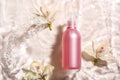 Bottle of cosmetic product and flowers in water on light background Royalty Free Stock Photo