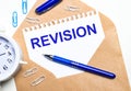 On a light background, a craft envelope, an alarm clock, paper clips, a blue pen and a sheet of paper with the text REVISION Royalty Free Stock Photo