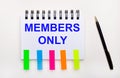 On a light background, a pen, a notebook with the text MEMBERS ONLY and bright stickers Royalty Free Stock Photo