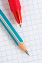 Light background on a school theme with place for text. Wooden pencil and red pen lie on a squared notebook sheet close-up. White Royalty Free Stock Photo