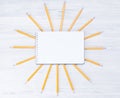 light background of simple pencils, notebook above, yellow sun