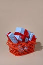 on a light background there is an orange shopping basket containing gifts in blue packaging