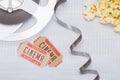 on a light background, unwound film with two tickets to the cinema and fresh popcorn Royalty Free Stock Photo