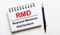 On a light background, a white notebook with are words RMD Required Minimum Distributions and a pen Royalty Free Stock Photo