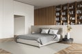 Light bedroom interior, grey bed with linens and coffee table, bookshelf on background