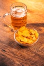 Light beer mug with a bowl of potato chips on a wooden table Royalty Free Stock Photo