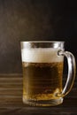 Light beer, beer mug with foam on a dark wooden background, alcoholic drink Royalty Free Stock Photo
