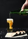 Light beer pours from a bottle into a glass, pieces of smoked mackerel Royalty Free Stock Photo