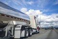 Light beige classic big rig semi truck transporting liquid cargo in tank semi trailer driving on the wide highway road Royalty Free Stock Photo