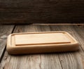 Light beige rectangular empty cutting kitchen board on a wooden background