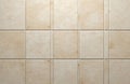 Light beige square ceramic tiles create a textured matt wall surface with a subtle stone imitation. The noisy pattern offers a Royalty Free Stock Photo